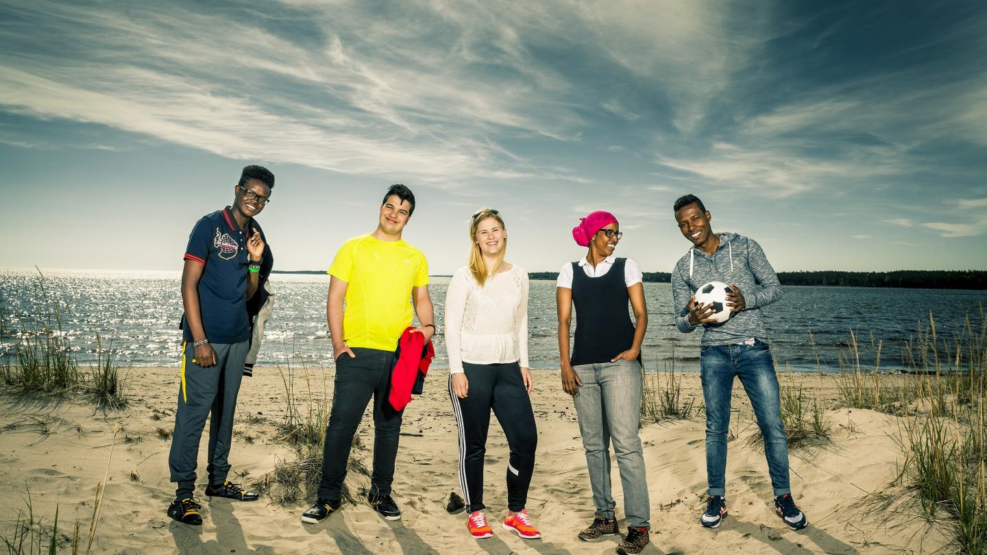 En grupp ungdomar stående på rad på en havsstrand.