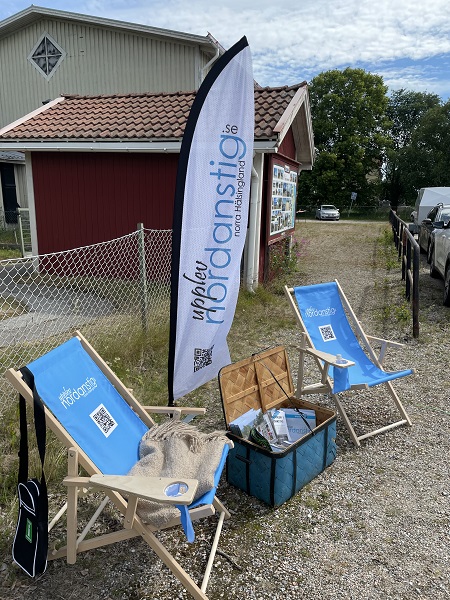Färgbild utomhus - våra stolar och beachflagga och broschyrkorg som används på våra turer ute i kommunen