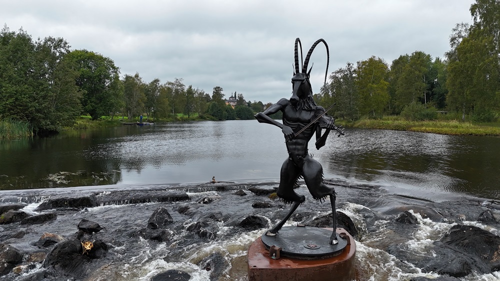 Färgbild - porträtt av Syndabocken i Bergsjö. En smidd hälsingebock-staty placerad i ett vattenflöde vid Bergebron i Bergsjö, Hälsingland. En symbol för folkmusiken, historiska traditioner, konsthantverk i norra Hälsingland, Sverige.