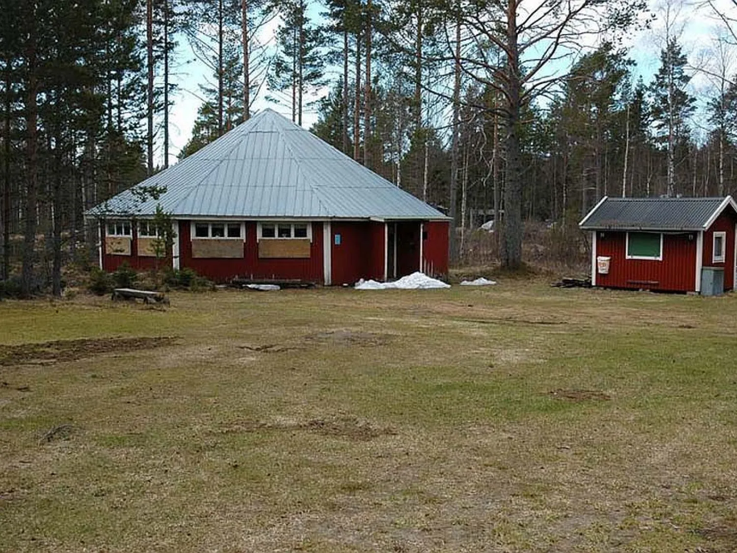 Färgbild - gammal dansrotunda i skogmiljö. Rödvit byggnad.