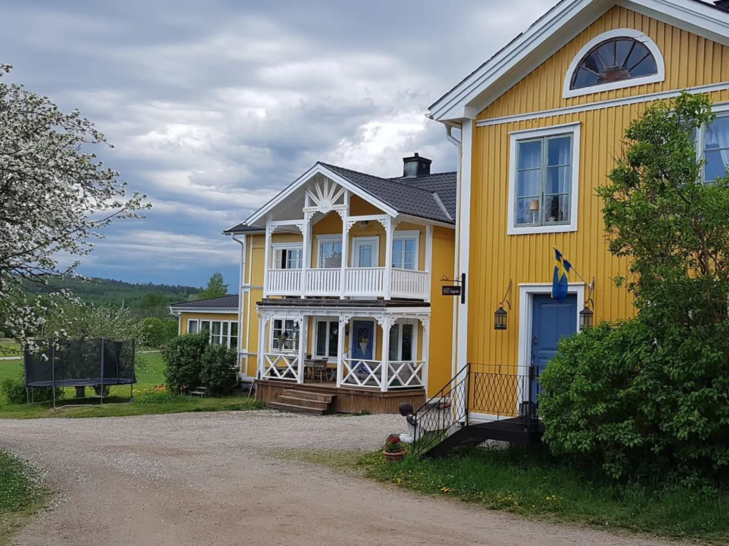 Färgbild - exteriör bild på gulvit hus med grönskande trädgård