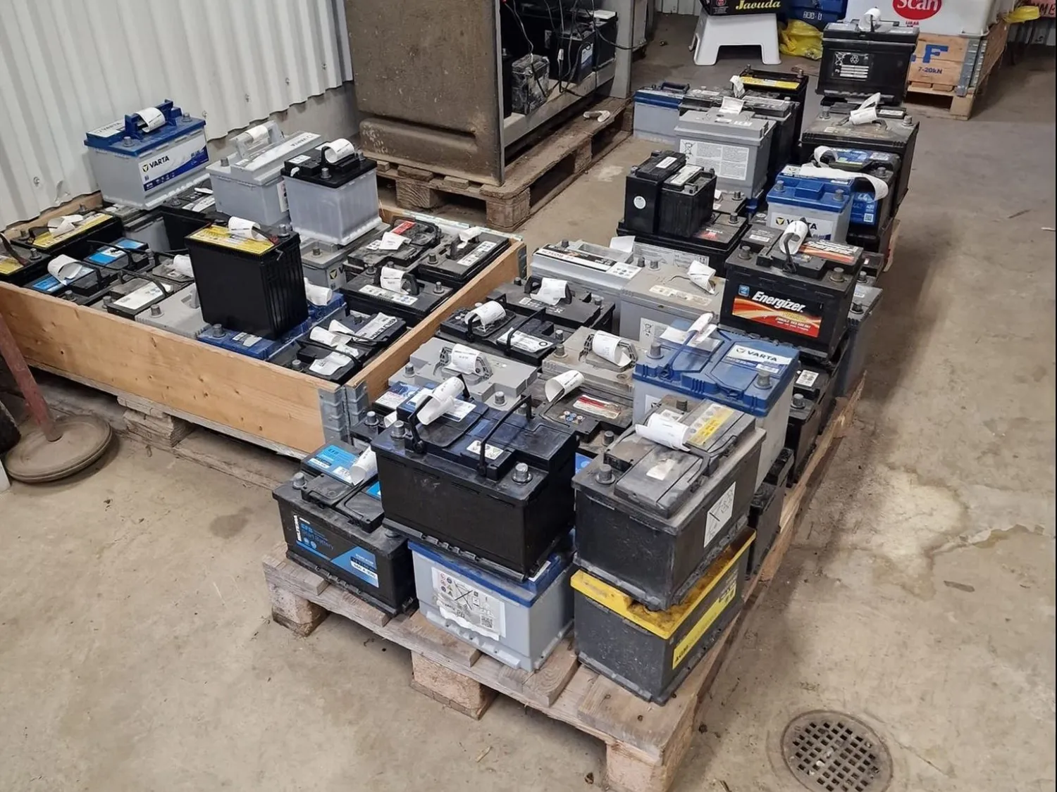 Färgbild - bilbatterier på träpall inomhus.