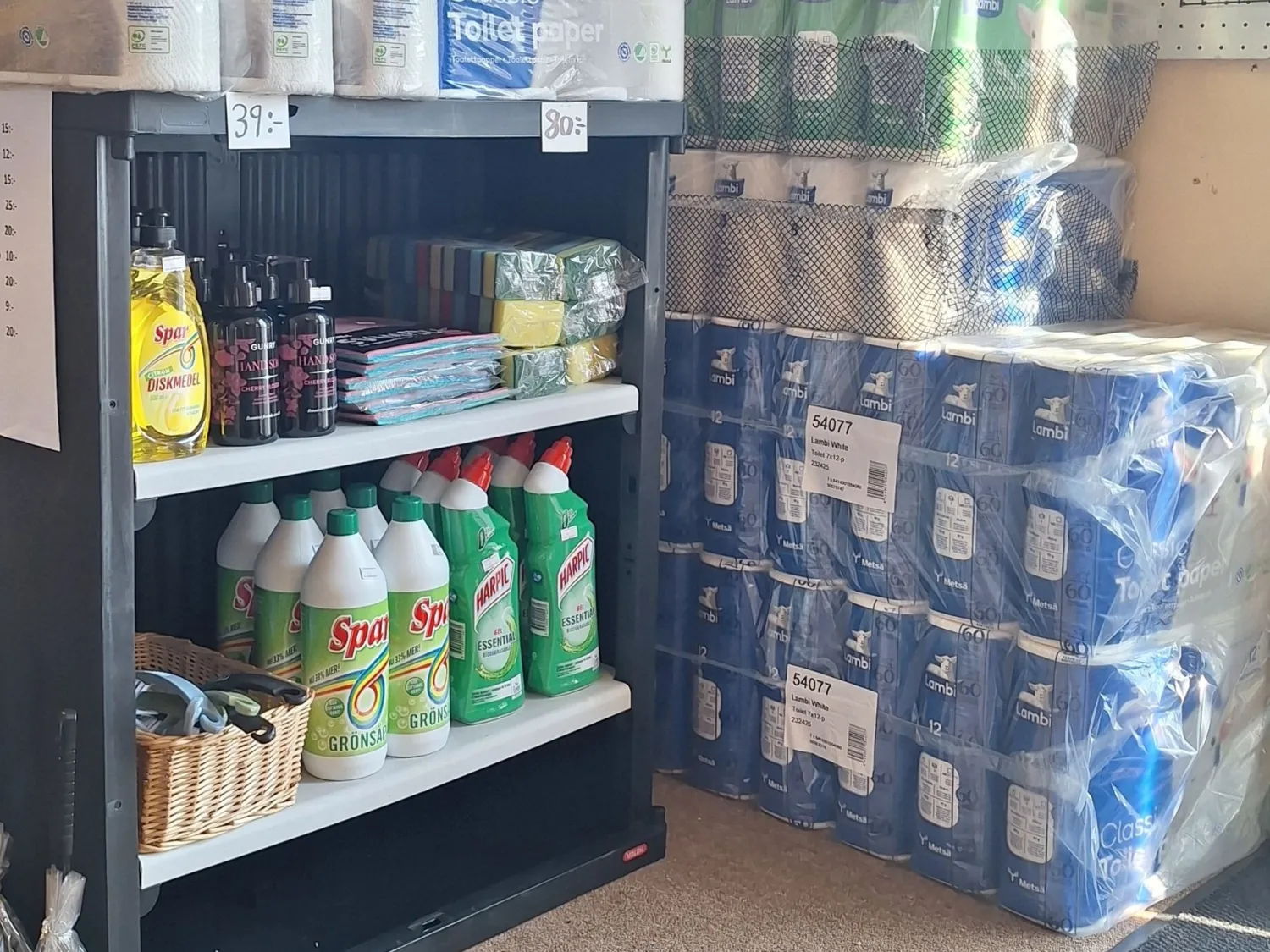 Färgbild - hushålls- och toalettpapper med flera varor på hylla i butik.