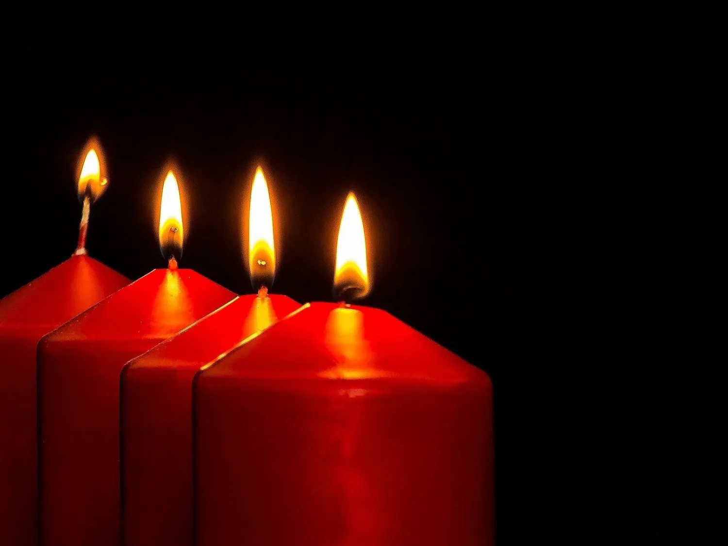 Juleljus - fyra tända ljus på rad. Mörk bakgrund