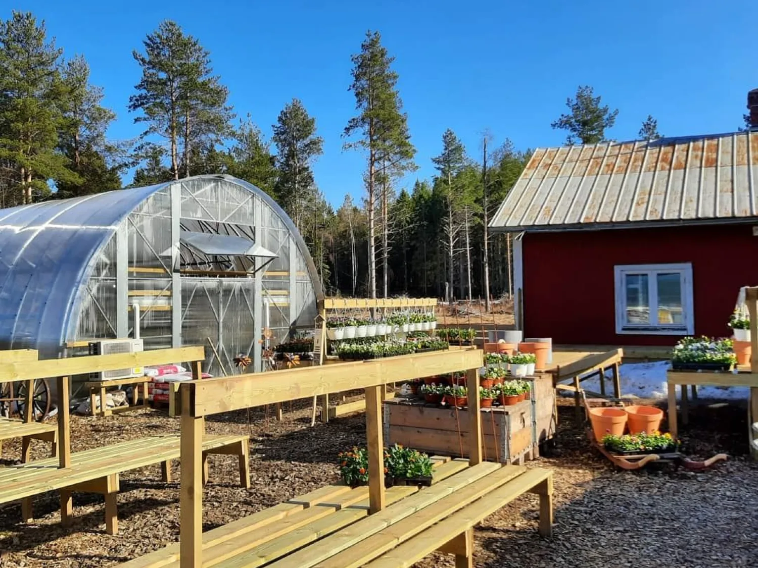 Utomhusbild med växthus och dela v röd byggnad.