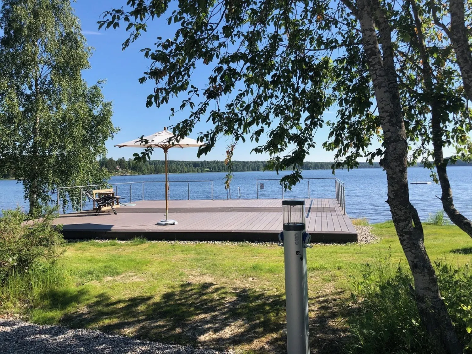 Utsikt över sjö med brygga och träd omgivande