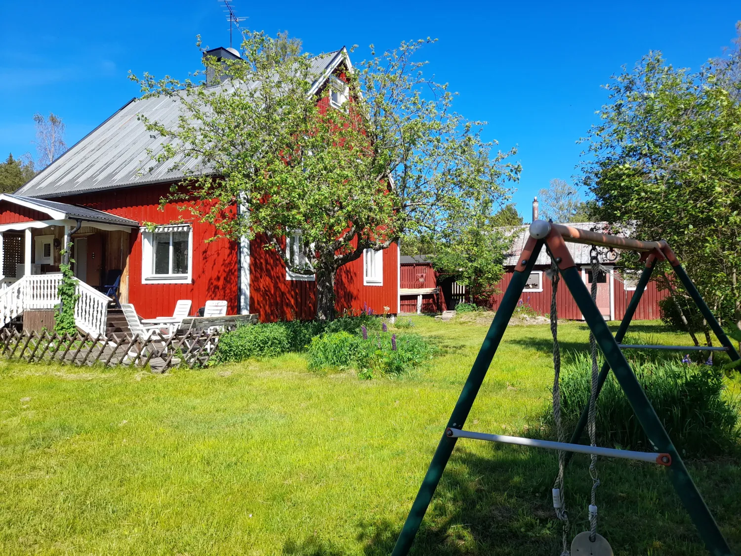 Utomhus, exteriör bild av rött hus i grönskande trädgård