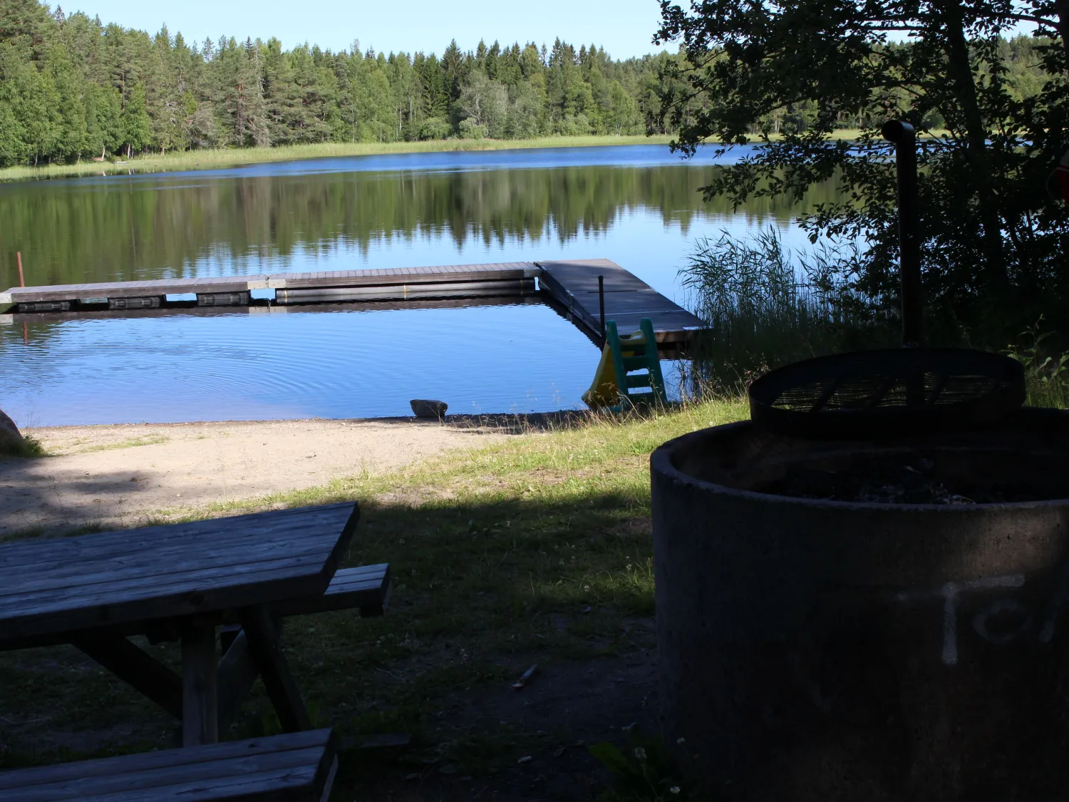 Grillplats med sittplats och brygga i bakgrunden