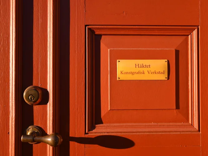 En röd dörr i närbild med textskylt.