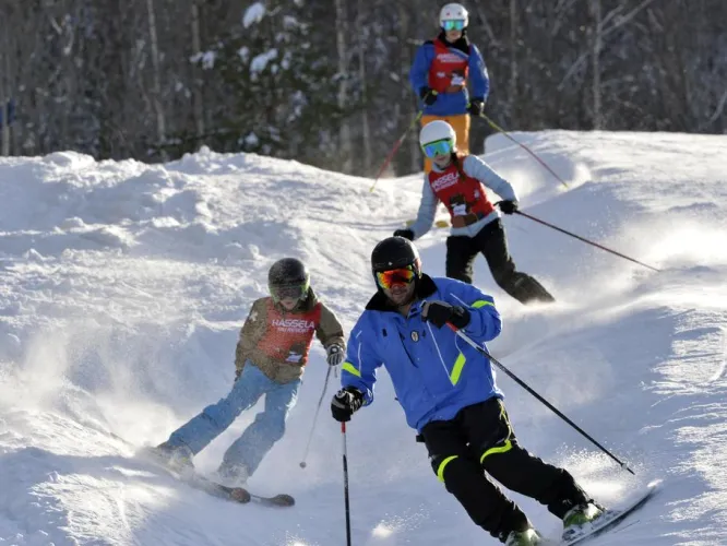 Färgbild - skidåkare i skidbacke. Länkad bild.