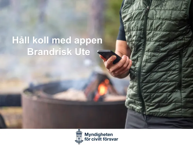 Färgbild - en man utomhus som håller en mobil. Eld i bakgrunden.