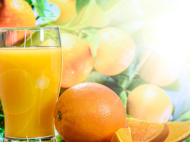 Ett glas apelsinjuice och färska apelsiner bredvid.