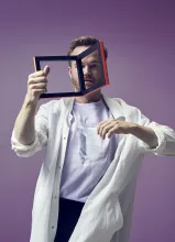 En man i vit rock hållande en ram högt i luften -