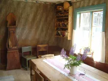 Interiör Ersk-Matsgården Interiör på Ersk-Matsgården - ett bord och stolar, moraklocka, köksredskap, lupiner i bukett på bordet
