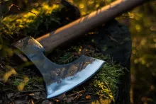 Yxa Fredrik Thelin Yxa liggande på en stubbe ute i skogen.