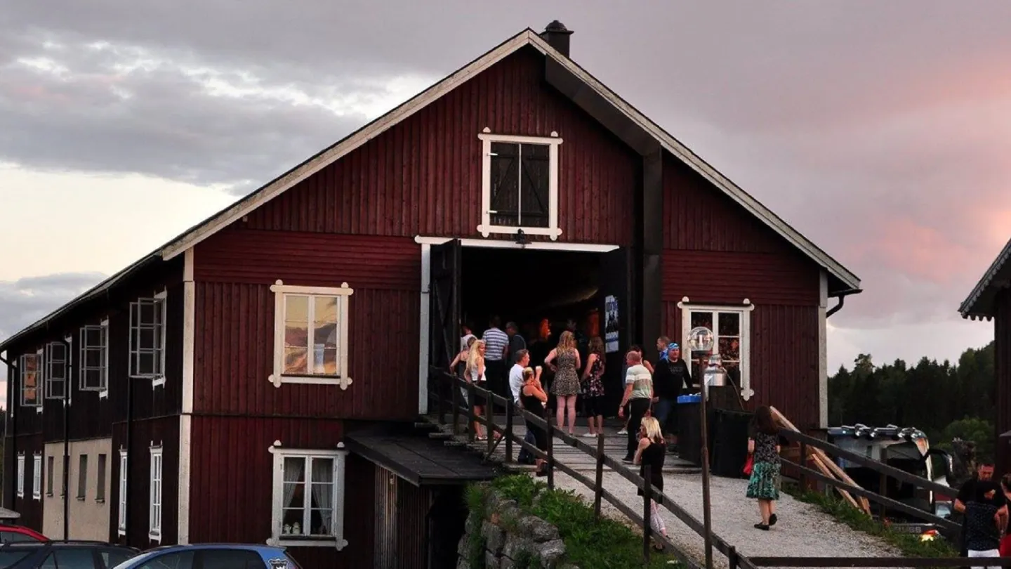 Människor på logdans i sommarkvällen, på väg uppför logbrygga.