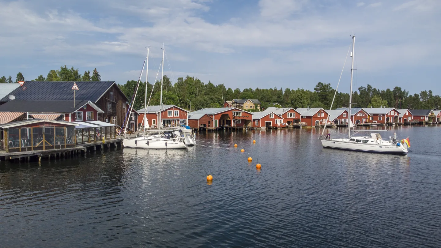 Färgbild - vy över Mellanfjärdens hamn med segelbåtar och sjöbodar
