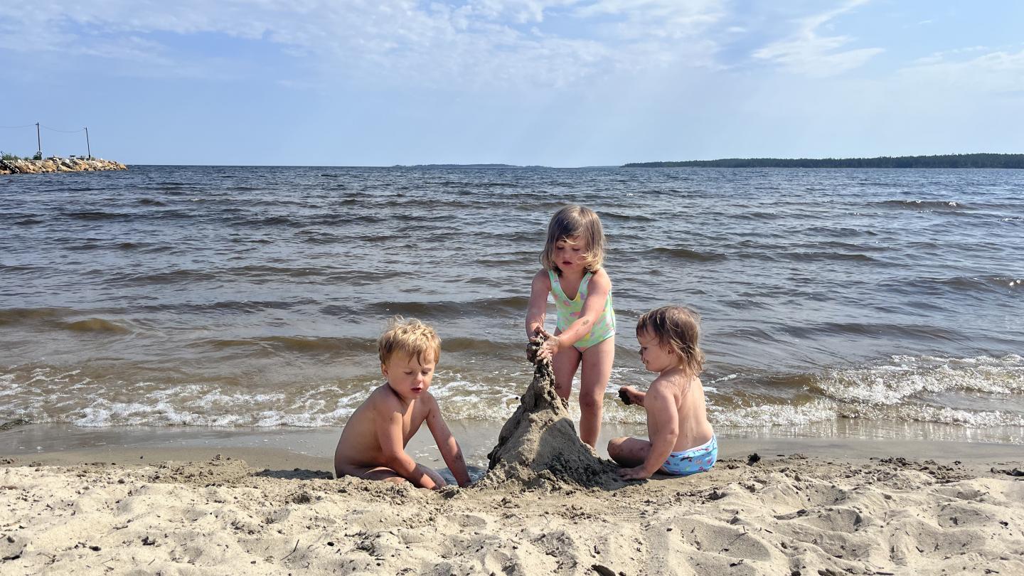 Tre barn som bygger sandslott på Sörfjärdens havsbad