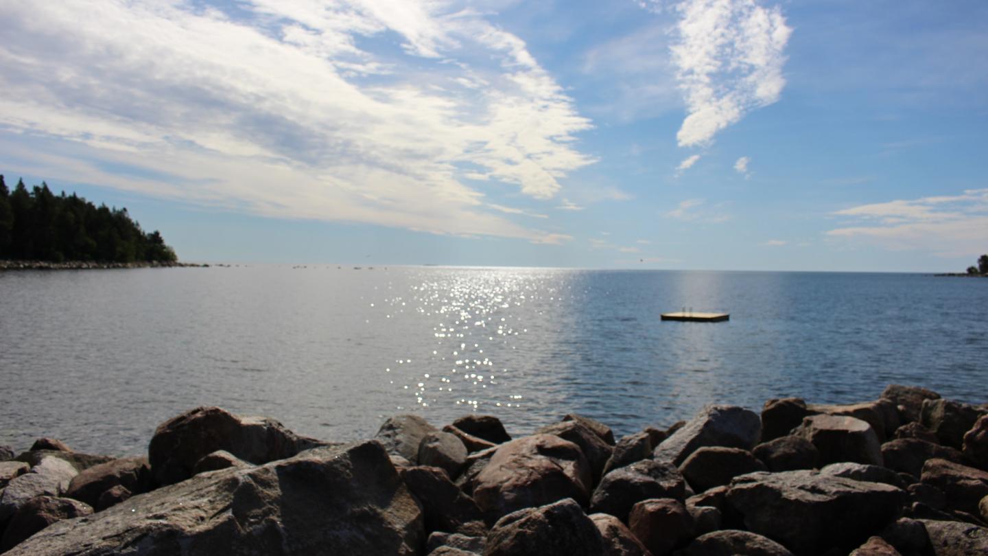 Havsutsikt Koffsand - stenig strand i förgrunden och havshorisonten möter himmel.