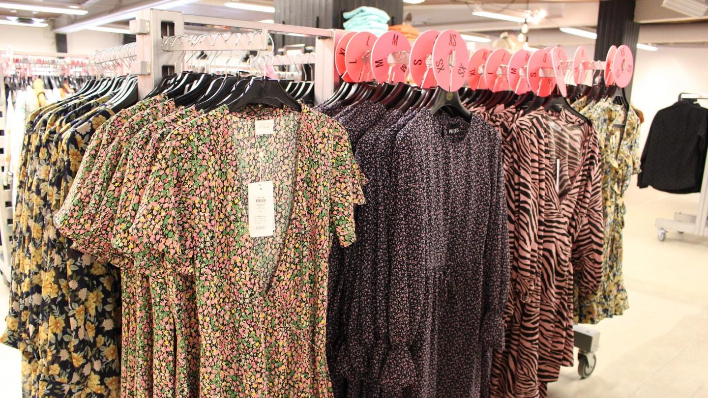 Inomhus - mönstrade kläder hängande på klädställningar i butik