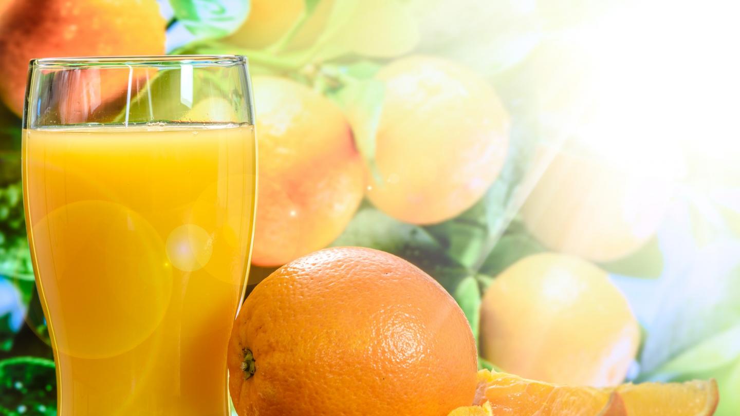 Ett glas med apelsinjuice och apelsiner